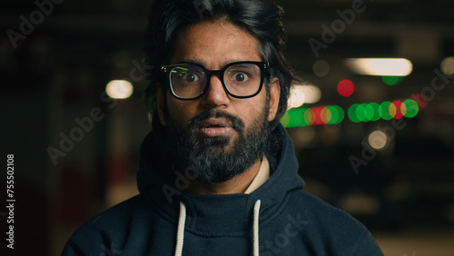 Emotional Indian shocked bearded guy in glasses astonished looking at camera at dark underground wonder amazed Arabian man shock fear scared say wow stunned big eyes open mouth bad news at parking lot