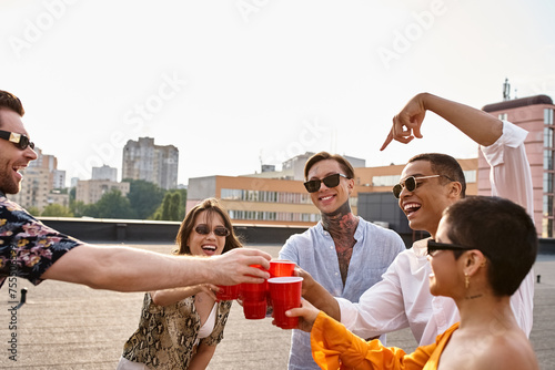 attractive cheerful interracial friends clinking their red cups next to DJ equipment at party