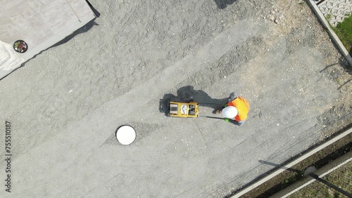 Aerial view above a man tamping foundation with vibratory plate - top down, drone shot photo