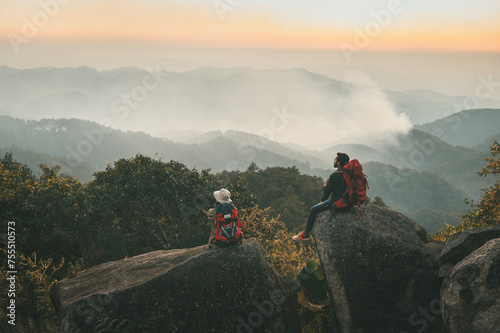 Two people are sitting on a rock in the mountains