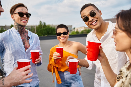 cheerful interracial friends with stylish sunglasses spending time together at rooftop party