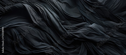 A dark black cloth is draped over a neatly made bed, creating a sleek and minimalist look in the room. The cloth hangs elegantly over the sides of the bed, adding a touch of sophistication to the