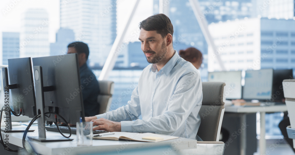 Happy Male Sales Manager Typing On Desktop Computer In Diverse Corporate Office With Megapolis Window View. Proffesional Caucasian Man Smiling After Closing Big Advertising Deal For E-commerce Company