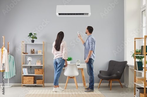 Obraz na plátně Family couple turn on air conditioning system at home