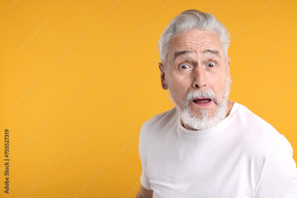 Portrait of surprised senior man on yellow background, space for text Portrait of surprised senior man on yellow background, space for text