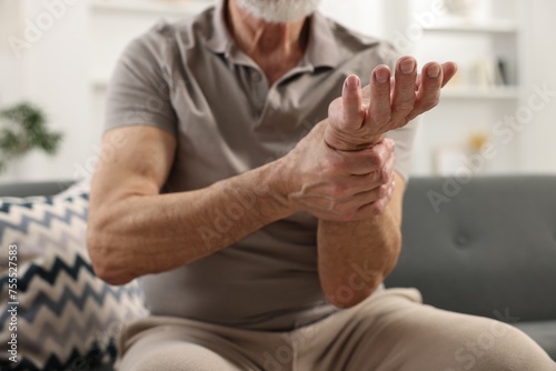 Arthritis symptoms. Man suffering from pain in wrist at home  closeup