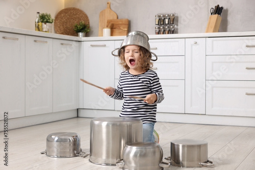 Slika na platnu Little girl pretending to play drums on pots in kitchen