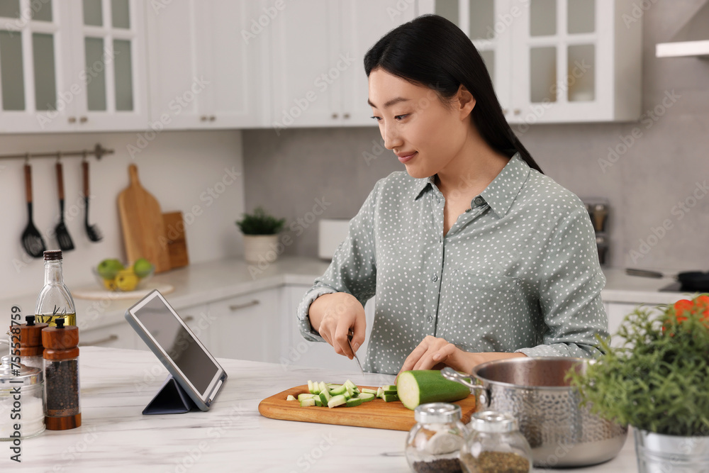 Beautiful woman looking at recipe on tablet while cooking in kitchen