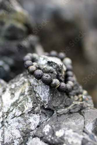 Bangle made from natural black stones for men or female fashion  outside on the rocks. Handcraft precious item. Jewelry accessories.