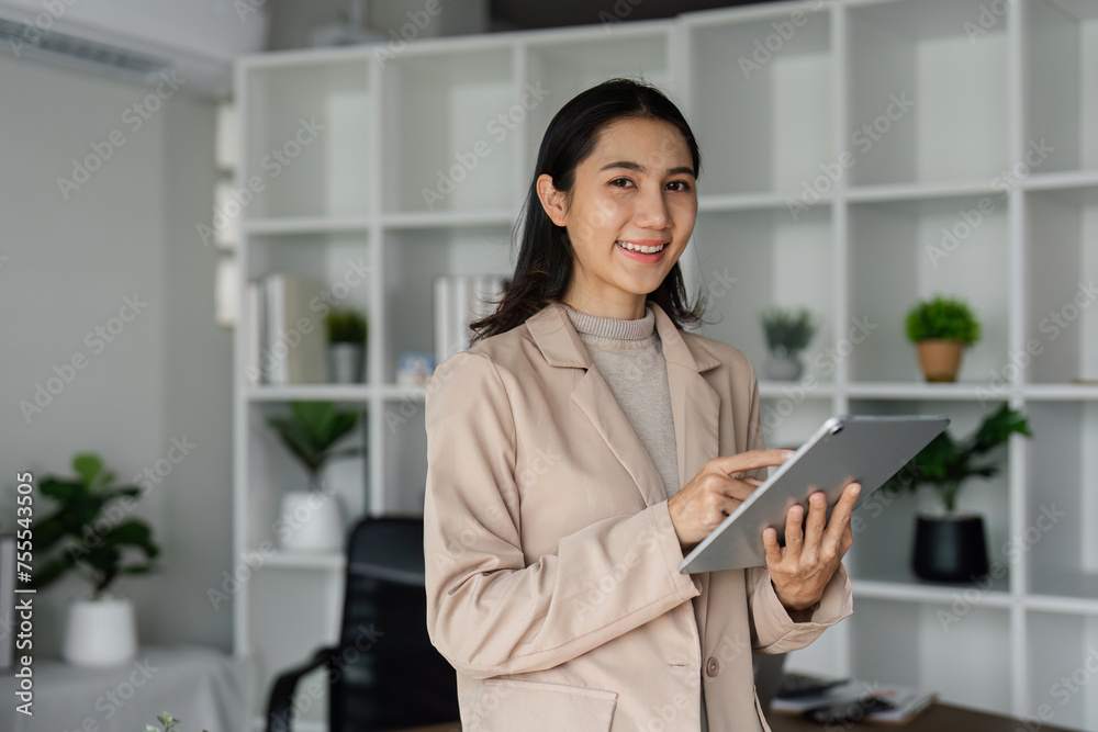 young asian woman, company worker in suit, smiling and holding digital tablet, standing over working space background young asian woman, company worker in suit, smiling and holding digital tablet, standing over working space background