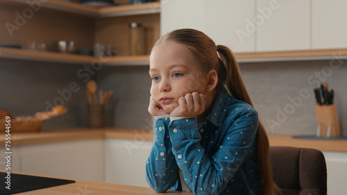 Portrait sorrow grief worried little offended Caucasian sad upset bored child girl schoolgirl orphan unhappy lonely kid at home kitchen alone depressed stressed daughter sadness family quarrel photo