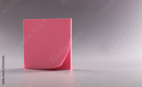 Closeup of block of pink note paper on gray background. Reminder concept