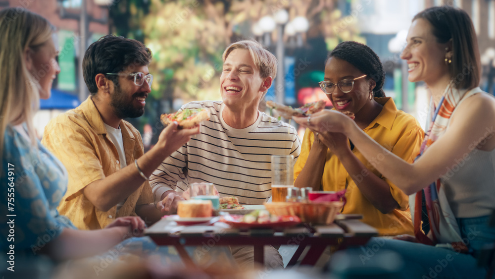 Multiracial Group of Friends Enjoying Leisure Time in a Street Cafe. Young Women and Men Having Fun Conversations Behind a Table, Enjoying Tasty Food and Beverages