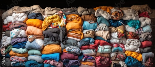 A collection of various clothing items stacked on a heap of blankets, creating a cluttered yet functional storage space for textile waste.