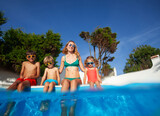 Family enjoying pool time together dangling legs in warm water