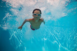 Kid boy with goggles swimming underwater joyfully after dive