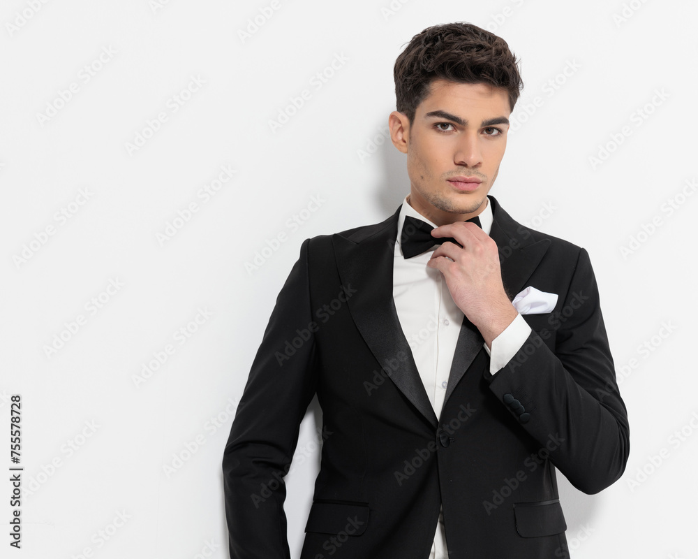 sexy young businessman in black tuxedo adjusting black bowtie sexy young businessman in black tuxedo adjusting black bowtie