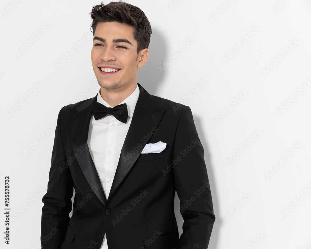 happy elegant groom in black tuxedo looking away and laughing happy elegant groom in black tuxedo looking away and laughing