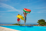 Dad and son with floaties jump to pool ready for summer fun