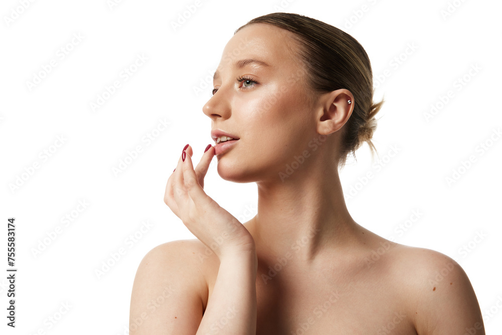 Young beautiful woman with bare shoulders gently touching her lips against white studio background. Profile view. Concept of natural beauty people, injections, wellness, spa procedures, cosmetology.