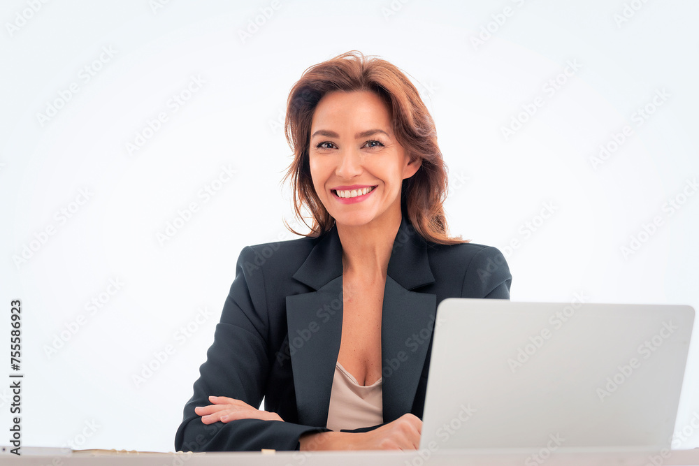 Studio shot of an attractive mid aged woman sitting at desk and using laptop against isolated white background Studio shot of an attractive mid aged woman sitting at desk and using laptop against isolated white background