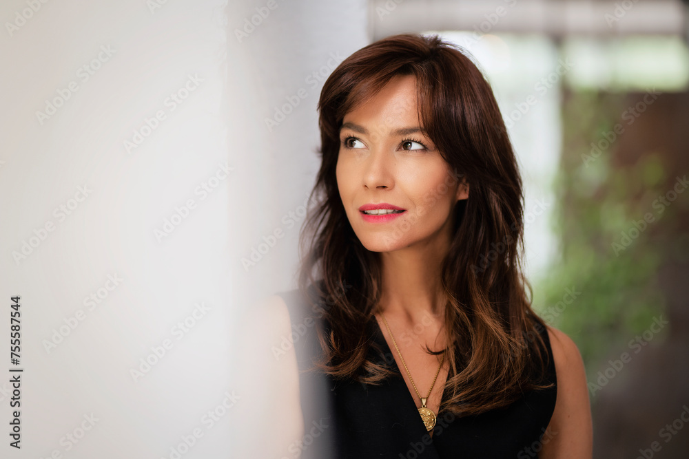 Portrait of an attractive woman looking away and smiling at the window Portrait of an attractive woman looking away and smiling at the window