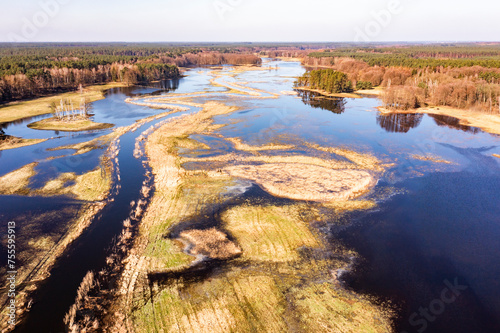 Fototapeta Naklejka Na Ścianę i Meble -  Flooded fields, meadows and forests during excessive rainfall. A river flooding fields and forests, view from a drone..