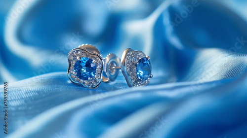 Pair of platinum earring with sapphire on blue.