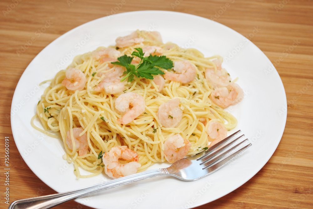 Shrimp scampi served on spaghetti and garnished with parsley.
