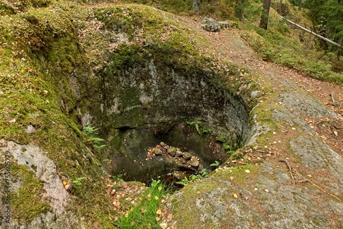 Cylindrical Talvia Giant´s kettles (giant´s cauldron, moulin pothole, or glacial pothole) drilled in solid rock in forest in autumn with leaves on the ground, Lohja, Finland. photo