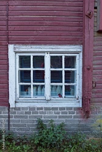 Wooden red wall with white painted frame window.