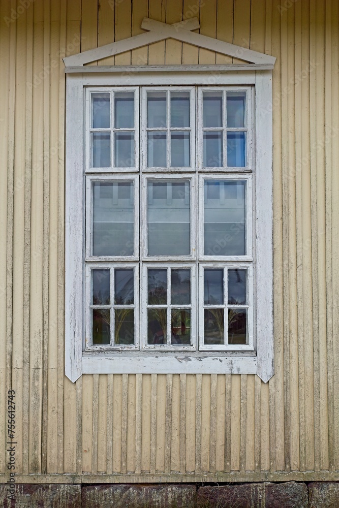 Old wooden yellow wall with white painted frame window.