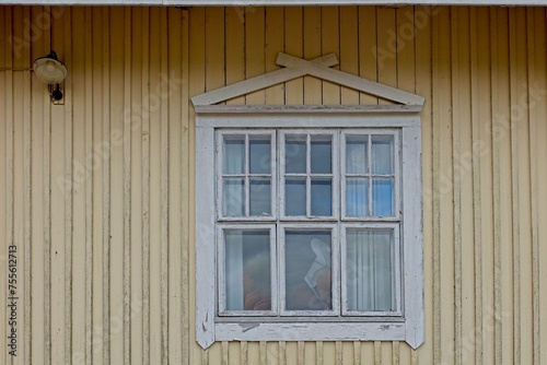 Old wooden yellow wall with white painted frame window.