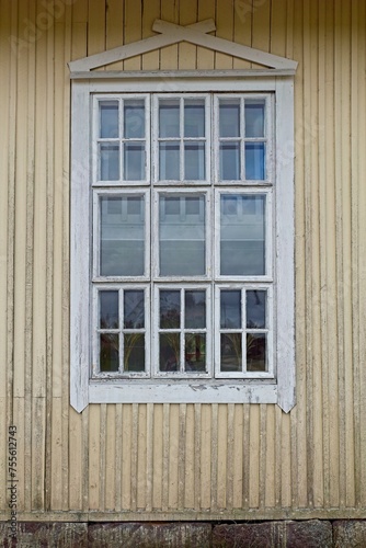 Old wooden yellow wall with white painted frame window.