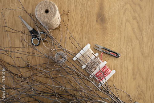 Supplies for making DIY wicker wreath of birch branches on wooden table background. Wreath weaving, handmade decoration