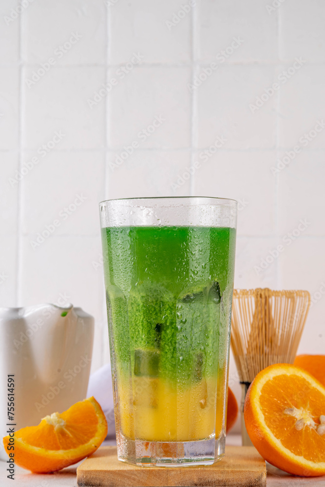 Fototapeta premium Orange Matcha Lemonade, Cold asia fruit cocktail with green matcha and orange citrus drink on white background, copy space