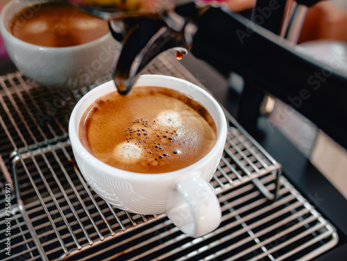 Close-up of espresso pouring from the coffee machine into a coffee cup. Professional coffee brewing coffee crema