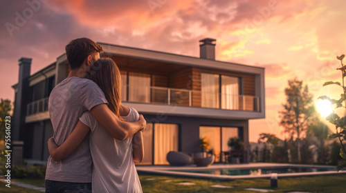 Happy young couple standing in front of new home. Couple looking their new house