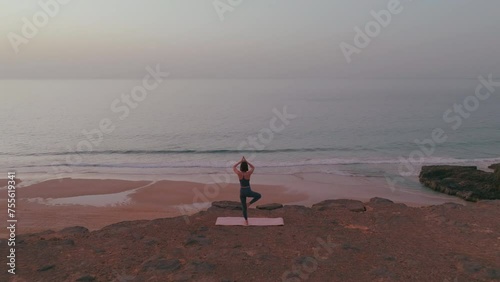 Aeiral push in shot, Girl doing yoga on the cliff by the ocean, Fuerteventura Spain