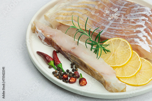 Raw pollock (Pollachius virens) fillet. Fresh fish for healthy food lifestyle. Spices and herbs photo