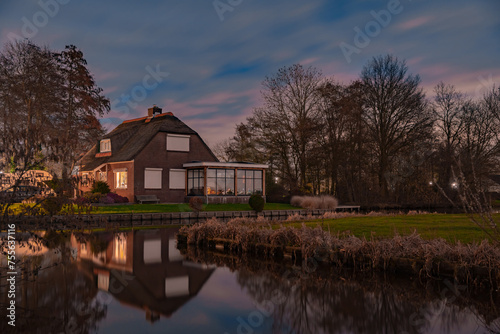 Night landscape with starry sky in the Dutch village of Streefkerk. Houses with bright light reflecting in the shine of the water in the autumn season