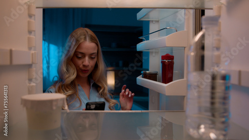 Point of view POV inside refrigerator Caucasian girl hungry woman open fridge at home kitchen look at empty shelves order food products delivery with mobile phone app online service web store shopping photo