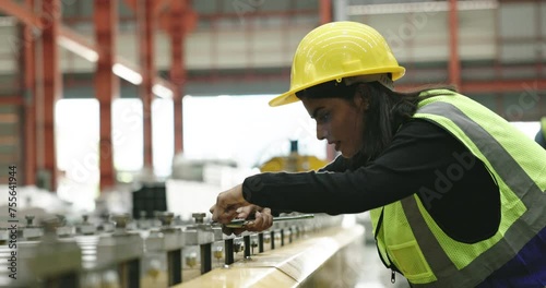 technician workers woman is using tools to service machine produces sheet metal in factory. Engineers are inspecting machines and repairing them profession. Wear safety helmet to prevent during work	