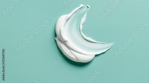 Smooth white skincare cream swipe in a checkmark shape on a mint background photo