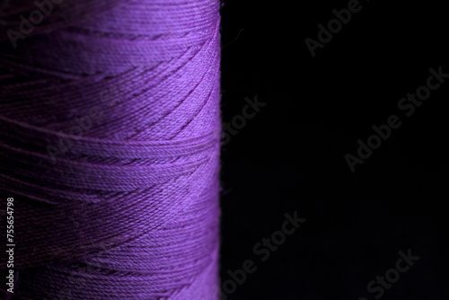 Spool of purple thread for sewing with black horizontal background photo