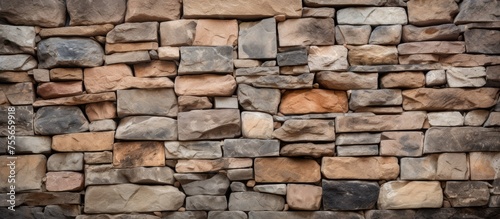 A stone wall constructed with alternating brown and tan stones arranged in a pattern, creating a sturdy and visually appealing structure.