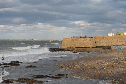 Heraklion-Crete, Greece- February 02 2021: A sunny day in Heraklion, in the bay of Dermatas. Beach view, with the old Venetian Walls touching the wave.