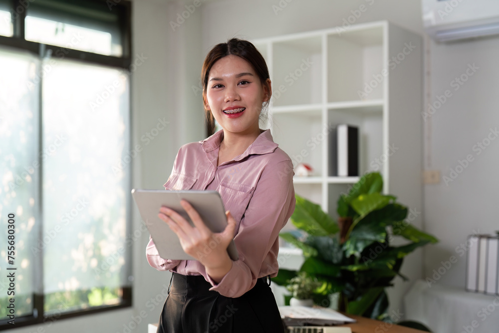 Young smiling successful employee business woman work use hold tablet stand at workplace desk at home office . Achievement career concept, green room area, lifestyle concept