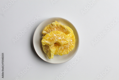 Dried pineapple sweets. Candied and dried pineapple. On small white plate. Isolated on white background, flat lay or top view