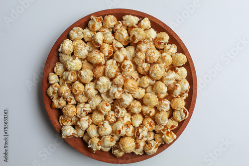 Caramel popcorn, on wooden plate, isolated on white background, flat lay or top view photo